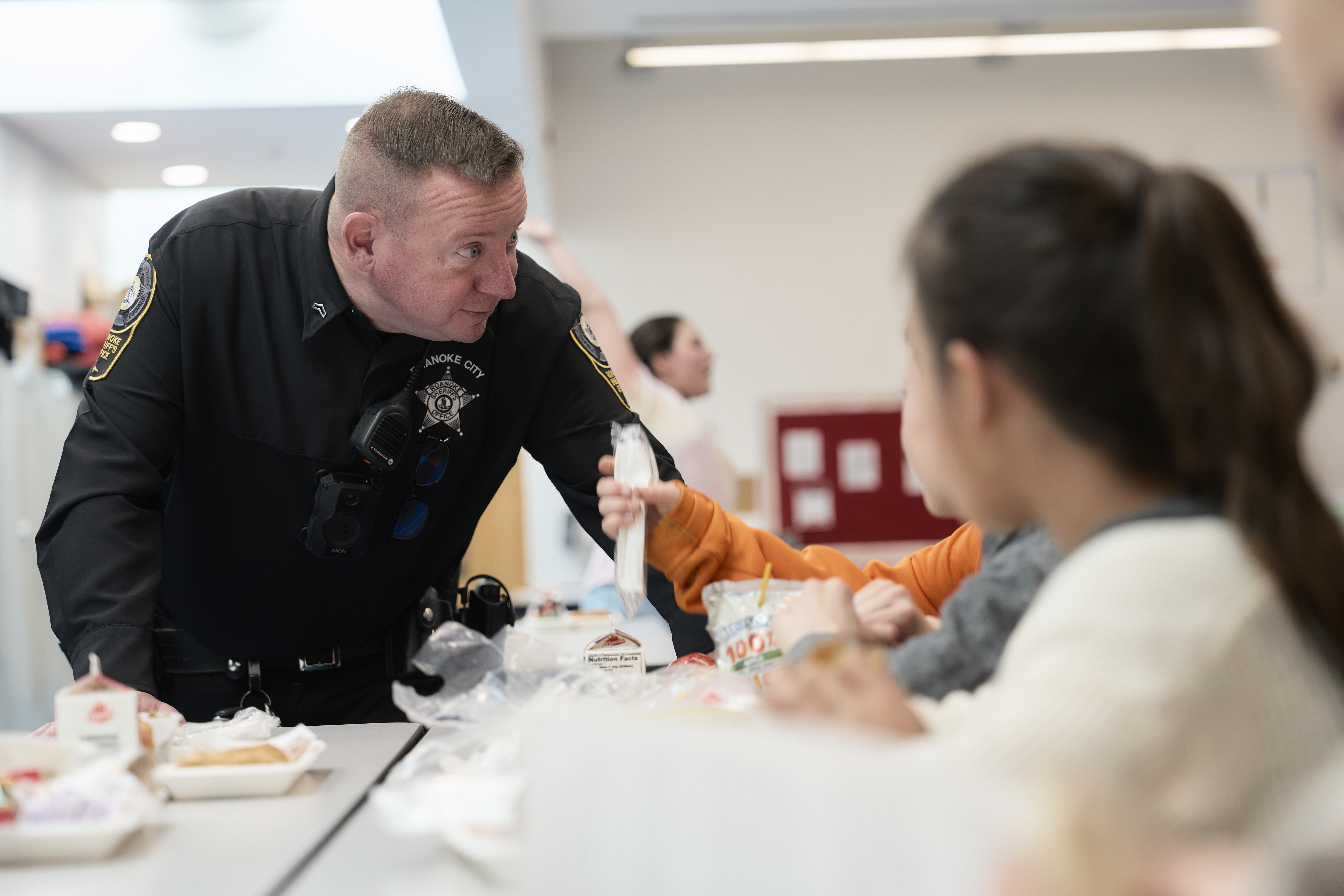 School resource officer talking to a student at lunch.